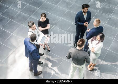 Ansicht von oben. Ein Team junger Geschäftsleute, die in einem Büro zusammenarbeiten und miteinander kommunizieren. Geschäftsleute und Manager in einem Meeting. Stockfoto