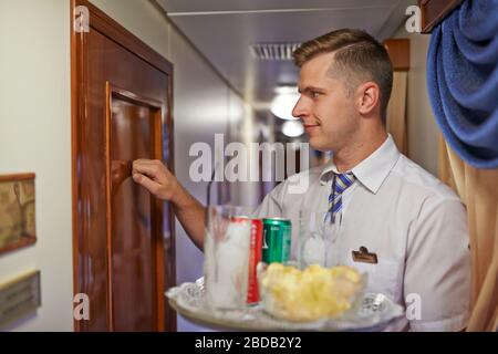 Zimmerservice in einem luxuriösen Transsibirischen Express; Leiter; Getränkeablieferung; Reinigung des Zimmers Stockfoto
