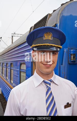 Zugleiter in einem luxuriösen Transsibirischen Express; Porträt eines uniformierten Schaffners auf dem Bahnsteig Stockfoto
