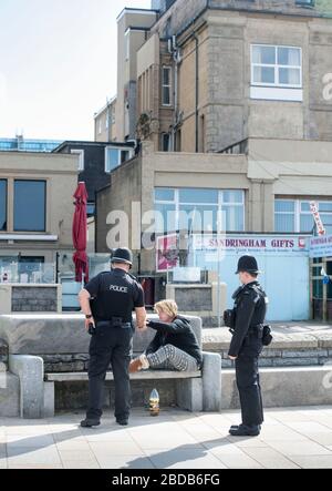 Die Polizei weist einen Obdachlosen an, während der Sperrung des Coronavirus in ihre Unterkunft in Weston-super-Stute zurückzukehren Stockfoto