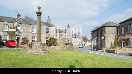 Das Marktkreuz und das Dorfgrün im Zentrum des Yorkshire Dales Dorfes Austwick Stockfoto