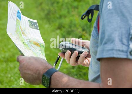 Mann hält einen GPS-Empfänger und plant in der Hand. Handheld-GPS-Geräte werden überwiegend in der Freizeitreisenbranche zum gehen und Wandern eingesetzt. Stockfoto