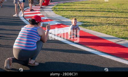 Mogyorod Ungarn 08 01 2019: Mutter fotografiert ihren Sohn auf den rot-weißen Gehwegen des Motor Speedway. Stockfoto