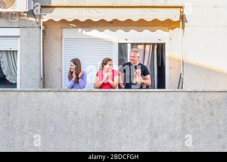 Huelva, Spanien - 7. April 2020: Bürger, die zu Hause bleiben und jeden Tag um 20 Uhr auf einem Balkon klatschen, während der Epidemiezeit des tödlichen Coronavirus. Stockfoto