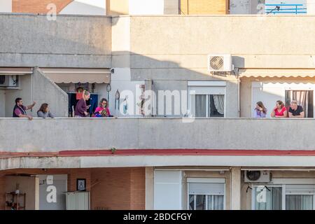 Huelva, Spanien - 5. April 2020: Bürger, die sich zu Hause aufhalten und jeden Tag um 20 Uhr auf die Balkone gehen, um während der Epidemiezeit der dea zu klatschen Stockfoto