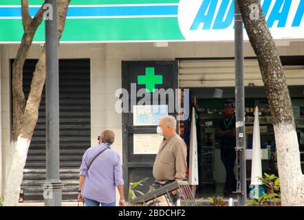 Caracas, Venezuela 31. März 2020: Menschen in einer fast leeren Straße, die Masken vor einem Apotheken-Drogerie-Geschäft während der Verbreitung von Cover 19 trägt Stockfoto