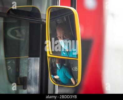 Ein Londoner Busfahrer, der eine Gesichtsmaske trägt. Mindestens 14 Transportarbeiter in London sind an der Covid-19 gestorben, was zu einem neuen Pilotprojekt geführt hat, bei dem Passagiere an Bord von Bussen kommen, die die mittlere Tür benutzen, um den Kontakt mit den Fahrern zu verringern. Stockfoto