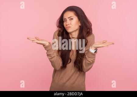 Wissen Sie vielleicht nicht, wer sich interessiert! Portrait von clueless verwirrte junge Frau mit welligem, brünettem Haar, das peinlich und uninteressiert in Frage aussieht, hes Stockfoto