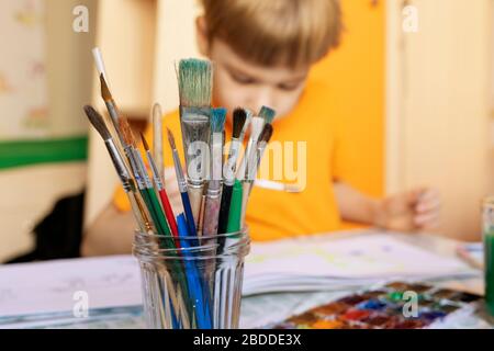 Malpinsel auf unscharfem Hintergrund von Farbe und Junge beschäftigen sich mit der Malerei. Kreative Aktivitäten für Kinder zu Hause. Freizeit zu Hause mit Kindern Stockfoto