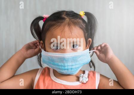 Kleines asiatisches Mädchen, das eine chirurgische Maske trägt. Konzept der Hitzeschutzbehandlung für Kinder und Infektionsschutz Stockfoto