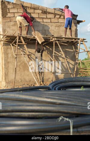 11.11.2019, Burferedo, Somali-Region, Äthiopien - Bauarbeiter stehen auf einem ungesicherten Holzgerüst und setzen Betonziegel. Im Vordergrund Stockfoto