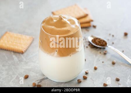 Dalgona Kaffee Creme mit Milch in Glasbecher mit Löffel im Hintergrund Stockfoto