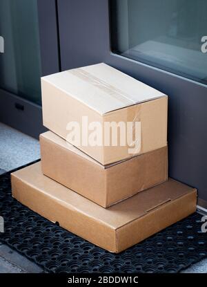 Pakete, die vor der Haustür zurückgelassen werden, um online gekaufte Artikel kontaktlos zu liefern Stockfoto