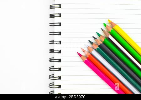 Verschiedene farbige Bleistiftkrebse, die in einer winkten Formularreihe vor einem weißen Papiertagebuch platziert wurden Stockfoto
