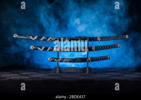 Katana, Wakizashi und Tanto auf einem Ständer, blauer Rauch dahinter Stockfoto