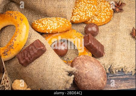 Bagels, Schokoladenkuchen, Plätzchen, Schokolade und Sternanis auf dem Grund grober Homespun-Qualität. Nahaufnahme Stockfoto