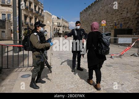 Israelische Grenzpolizisten tragen Schutzmasken, die die ID einer israelischen Araberin in einem Kontrollpunkt tragen, der während des Ausbruchs der Coronavirus-Krankheit (COVID-19) in Israel in der Altstadt von Jerusalem aufgestellt wurde. Stockfoto