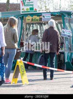 Nordhorn, Deutschland. April 2020. Besucher eines Wochenmarktstandes an einem Stand in deutlich größerer Entfernung. Auch auf den Wochenmärkten werden die Abstandsregeln während der Coronakrise eingehalten. Credit: Friso Gentsch / dpa / Alamy Live News Stockfoto