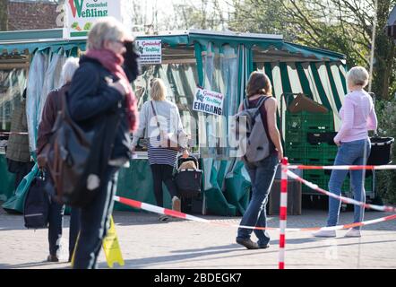 Nordhorn, Deutschland. April 2020. Besucher eines Wochenmarktstandes an einem Stand in deutlich größerer Entfernung. Auch auf den Wochenmärkten werden die Abstandsregeln während der Coronakrise eingehalten. Credit: Friso Gentsch / dpa / Alamy Live News Stockfoto