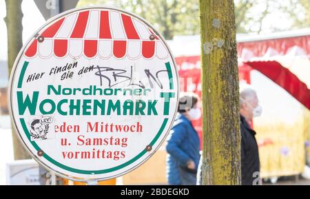 Nordhorn, Deutschland. April 2020. Besucher eines Wochenmarktstandes an einem Stand mit Gesichtsmasken. Auch auf den Wochenmärkten werden die Entfernungsregeln während der Coronakrise eingehalten. Credit: Friso Gentsch / dpa / Alamy Live News Stockfoto