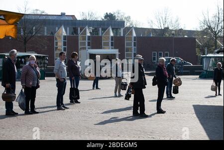 Nordhorn, Deutschland. April 2020. Besucher eines Wochenmarktstands an Ständen, die Gesichtsmasken tragen und auseinander liegen. Auch auf den Wochenmärkten werden die Fernregeln während der Coronakrise eingehalten. Credit: Friso Gentsch / dpa / Alamy Live News Stockfoto