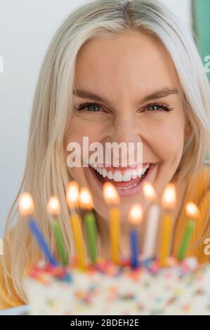 Frau lächelt hinter Geburtstagskerzen Stockfoto