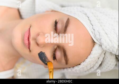 Gesichtsmaske wird auf das Gesicht der Frau im Spa angewendet Stockfoto
