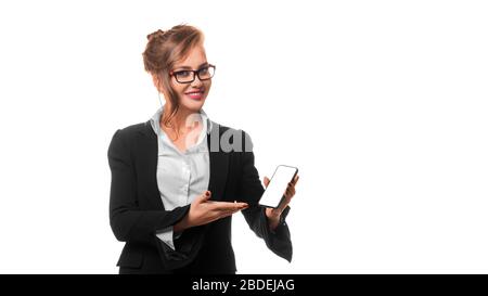 Lächelnde Geschäftsfrau in Brillen zeigt etwas auf dem Bildschirm eines Mobiltelefons. Mock-up. Isoliert auf weißem Hintergrund Stockfoto