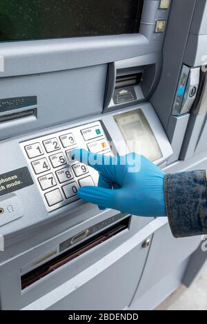 Nahaufnahme ofÂ Hand mit Handschuhen auf der Tastatur des Geldautomaten Stockfoto