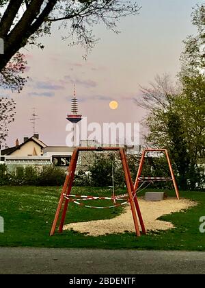 Frankfurt am Main in der Zeit des Corona-Virus Covid-19. Fernsehturm Europa aus Park an der Nidda Fluss Nidda am Abend mit Vollmond Stockfoto