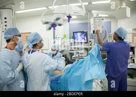 NHS Chirurgen führen laparaskopische Operationen am Magen eines Patienten durch, während sie den Fortschritt auf einem Monitor überprüfen. Stockfoto