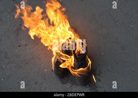 Brennende Schuhe aus nächster Nähe. Brennende Arbeitsschuhe Schuhe. Stockfoto