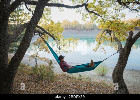 Italien, Mann liegt in der Hängematte in der Nähe des Sees Stockfoto