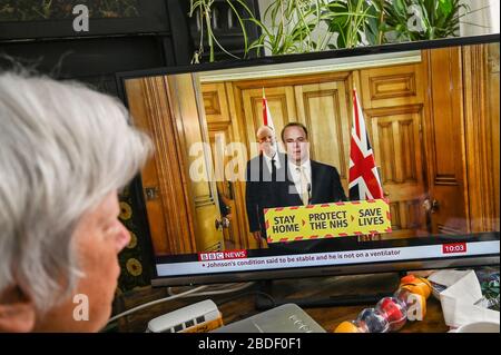 Dominic Raab gab eine Fernseh-Pressekonferenz über Covid-19, mit Chris Whitty (Chief Medical Officer), beobachtet von einer älteren Frau. Stockfoto