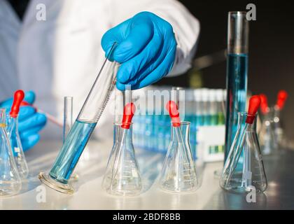 Forscher, der auf blaue flüssige Substanz im Reagenzglas schaut. Schwerpunkt auf Reagenzglas. Stockfoto