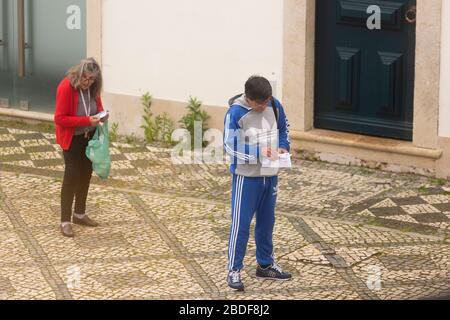 Olhão, Portugal, 8. April 2020. Menschen auf der Straße halten als Schutzmittel einen sicheren Abstand und halten den Ausbruch der COVID-19 ein Stockfoto