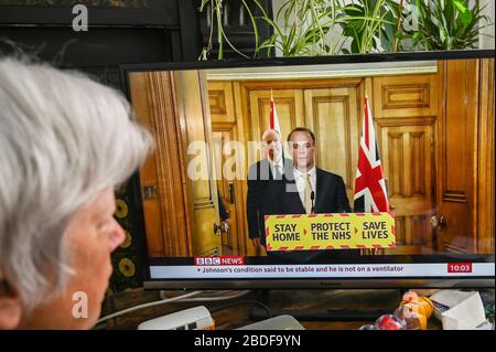 Dominic Raab gab eine Fernseh-Pressekonferenz über Covid-19, mit Chris Whitty (Chief Medical Officer), beobachtet von einer älteren Frau. Stockfoto