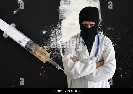 Arzt mit Diebemaske mit Drogen im Hintergrund. Konzept für medizinische Fehlpraktiken. Stockfoto