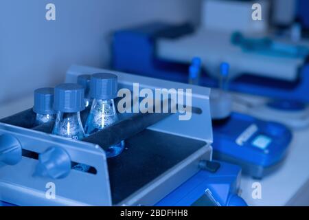 Nahaufnahme eines Labortisches mit Glaskolben und wissenschaftlichen Instrumenten in Blautönen. Das Konzept der wissenschaftlichen Forschung und Entwicklung. Stockfoto