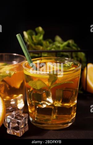 Frischer Cocktail Cuba Libre oder Whiskey Cola Cocktail mit braunem Rum, Cola, Minze und Limette auf schwarzem Hintergrund. Long Island Iced Tea Cocktail. Stockfoto