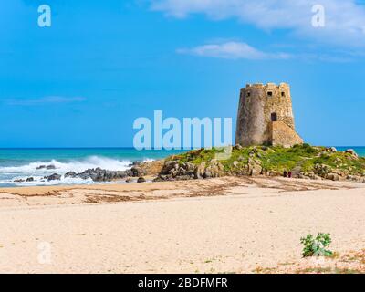 Das Wahrzeichen der Stadt Bari Sardo, der Torre di Barì, ein Turm, der auf einem Felsvorsprung am Strand mit beigem Sand und kristallklarem Wasser erbaut wurde Stockfoto