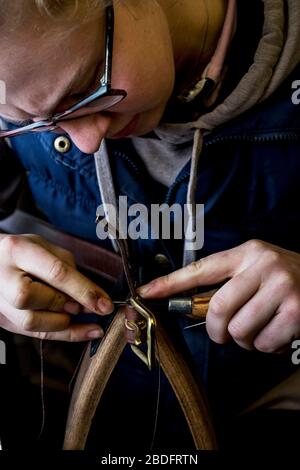 Nahaufnahme des in der Werkstatt stehenden Sattlers, Arbeiten am Lederriemen. Stockfoto