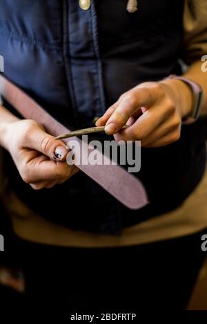 Nahaufnahme des in der Werkstatt stehenden Sattlers, Arbeiten am Lederriemen. Stockfoto