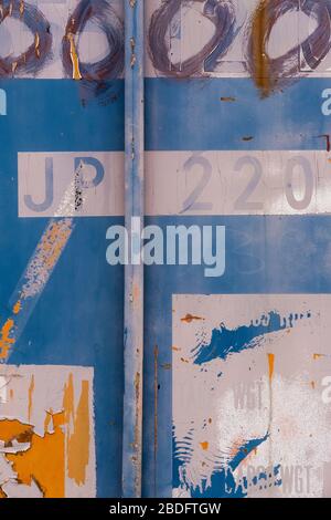 Detail der abblätternden Farbe und Markierungen auf farblich lackierten industriellen Frachtcontainern Stockfoto
