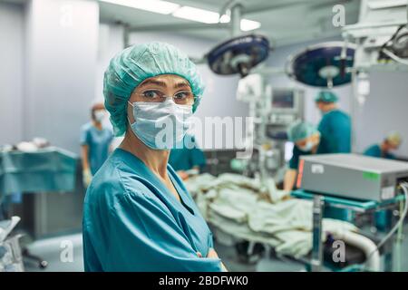 Porträt einer Chirurgen, Operation im Hintergrund. Chirurgie Medizin Konzept. Weibliche Chirurgen, Gleichstellung der Geschlechter, Leben retten. Schönheit und Gesundheit Stockfoto