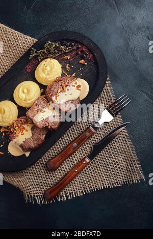 Köstliches zartes Schweinekotelett mit Kartoffelpüree, traditionelle italienische Küche. Essen Foto, Holz Hintergrund. Low-Taste. Draufsicht des Kopierbereichs Stockfoto