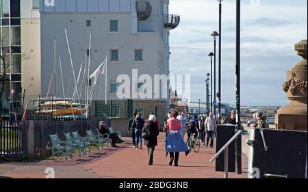 Portobello Beach, Edinburgh, Schottland, Großbritannien. April 2020. 18 Grad und voller Sonnenschein brachten Sonnenanbeter ans Meer, die meisten sozialen Distanzierungen, aber nicht die Menschenmassen, die erwartet würden, wenn es nicht den Coronavirus Lockdown gäbe und die Menschen hauptsächlich spazieren oder sitzen, anstatt auf dem Sand zu liegen. Ein männlicher und weiblicher Polizist auf der Promenade für einen Routinepassgang. Credit: Arch White/Alamy Live News Stockfoto