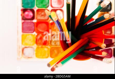 Aquarellfarbe, gut verwendete Bürsten, Bleistifte im Halter auf weißem Hintergrund. Zurück zur Schule, Heimschulkonzept Stockfoto