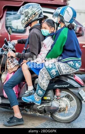 Ein junges thailändisches Schulmädchen wird von der Schule abgeholt und mit dem Motorrad durch die Straßen von Chiang Mai Thailand gefahren. Stockfoto