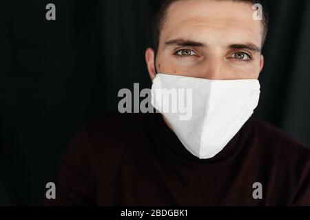 Ernster Mann in der schützenden medizinischen Maske auf dem schwarzen Rücken Stockfoto